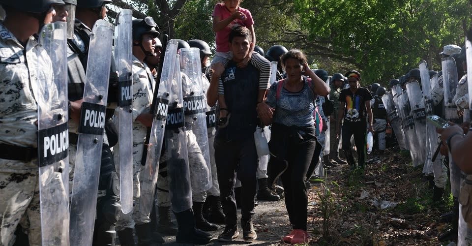 Familia migrante caminando entre elementos de la Guardia Nacional