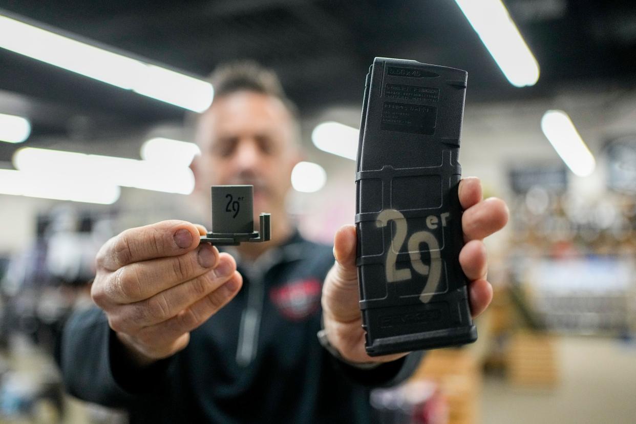 With the city of Columbus banning 30-round gun magazines, L.E.P.D. Firearms & Range owner Eric Delbert holds up a modified magazine that holds 29 rounds and the plastic single shot limiter that keeps it within the law in this March 7 photo.