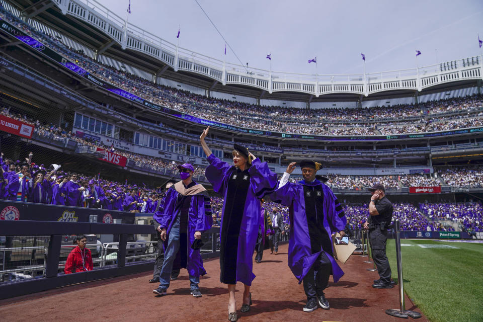 Taylor Swift, centro, saluda a graduados al participar en una graduación en de la Universidad de Nueva York en el Yankee Stadium en Nueva York, el miércoles 18 de mayo de 2022. (Foto AP/Seth Wenig)