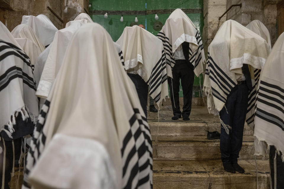 Jewish worshippers pray during the weeklong Jewish holiday of Sukkot, next to one of the gates to the Temple Mount, known to Muslims as the Noble Sanctuary, or the Al-Aqsa Mosque compound, in the Old City of Jerusalem, Wednesday, Oct. 4, 2023. (AP Photo/Ohad Zwigenberg)