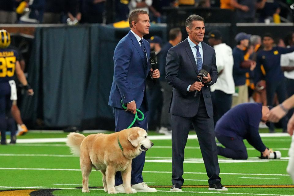 ESPN analyst Kirk Herbstreit walks his dog Ben with ESPN host Chris Fowler before the 2024 College Football Playoff national championship game between the Michigan Wolverines and the Washington Huskies at NRG Stadium.