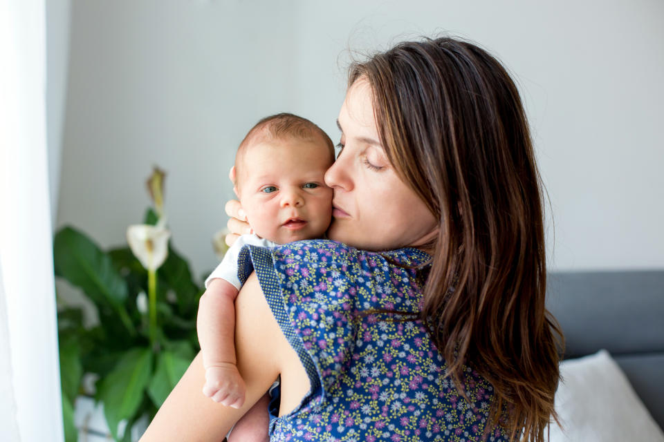 Young mother, kissing and hugging her newborn baby boy, tender, care, love, positive emotions