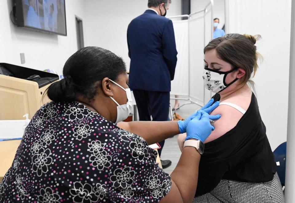 Kendra Gray, left, administers a COVID vaccine to Rachel Willis during a tour by N.C. Gov. Roy Cooper, rear.