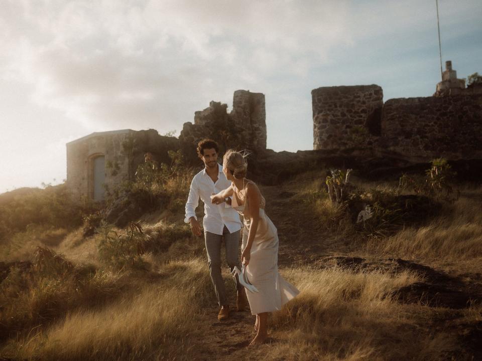 A couple look at each other and laugh as they walk down a hill.