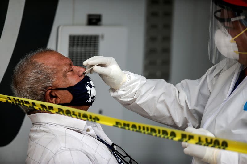 A healthcare worker collects a swab sample from a man to be tested for the coronavirus disease COVID-19 at a drive-thru testing site in Monterrey