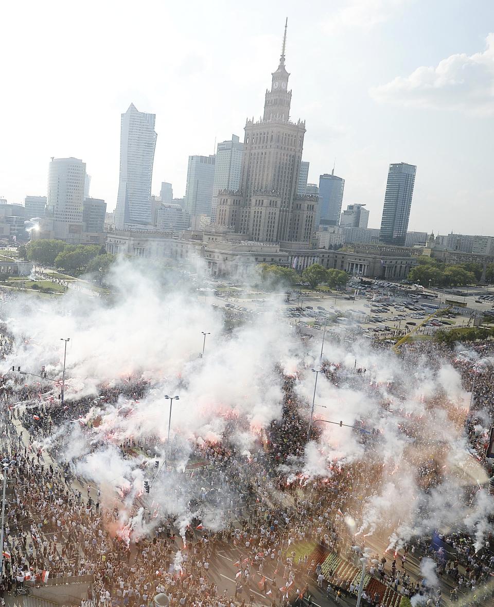 Warsaw residents stand with national flags and flares to observe a minute of silence for the fighters and victims of the 1944 Warsaw Rising against the Nazi German occupiers, on the 74th anniversary of the revolt, in downtown Warsaw, Poland, Wednesday, Aug. 1, 2018. (AP Photo/Czarek Sokolowski)