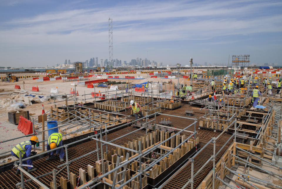 In this Wednesday, Oct. 31, 2018 picture, men work on the construction site of the Ras Abu Aboud stadium, backdropped by the city skyline in Doha, Qatar. Eight stadiums scattered in a 30-mile radius that will host 32 teams from across the planet are in various stages of development, most of them trying to walk the treacherous line of paying homage to the region's history while simultaneously avoiding becoming an expensive and unused relic once the party ends and everyone else goes home.(AP Photo/Vadim Ghirda)