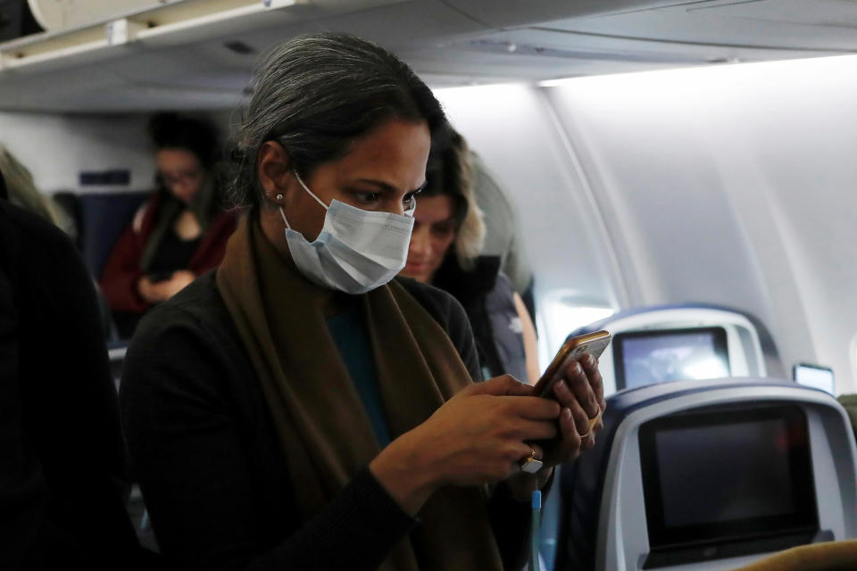 A woman in a face mask checks her phone after landing on a flight from San Francisco to New York City, after further cases of coronavirus were confirmed in New York, at JFK International Airport in New York, U.S., March 5, 2020. REUTERS/Shannon Stapleton