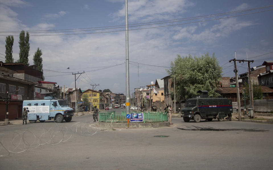 Indian policemen and paramilitary soldiers stand by their parked armored vehicles during curfew in Srinagar, Indian controlled Kashmir, Tuesday, Aug. 4, 2020. Authorities clamped a curfew in many parts of Indian-controlled Kashmir on Tuesday, a day ahead of the first anniversary of India’s controversial decision to revoke the disputed region’s semi-autonomy. Shahid Iqbal Choudhary, a civil administrator, said the security lockdown was clamped in the region’s main city of Srinagar in view of information about protests planned by anti-India groups to mark Aug. 5 as “black day." (AP Photo/Mukhtar Khan)