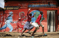 FILE - In this June 3, 2020, file photo, children run down a street past an informational mural warning people about the dangers of the new coronavirus, in the Kibera slum, or informal settlement, of Nairobi, Kenya. Africa’s confirmed coronavirus cases have surpassed 1 million, but global health experts tell The Associated Press the true toll is several times higher. (AP Photo/Brian Inganga, File)