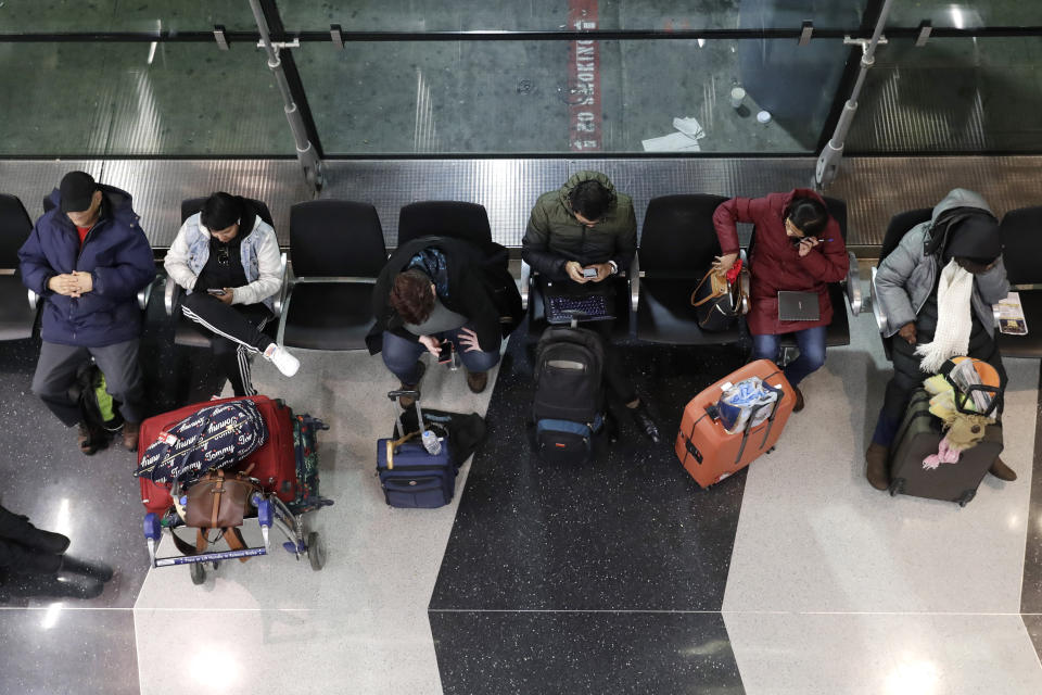 Travelers sit as they wait for their flight at O'Hare airport in Chicago, Friday, Jan. 17, 2020. Hundreds of flights canceled as winter storm hits city during evening commute Friday, creating sloppy rush hour. (AP Photo/Nam Y. Huh)