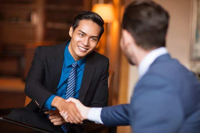 A smiling man shakes the hand of another man