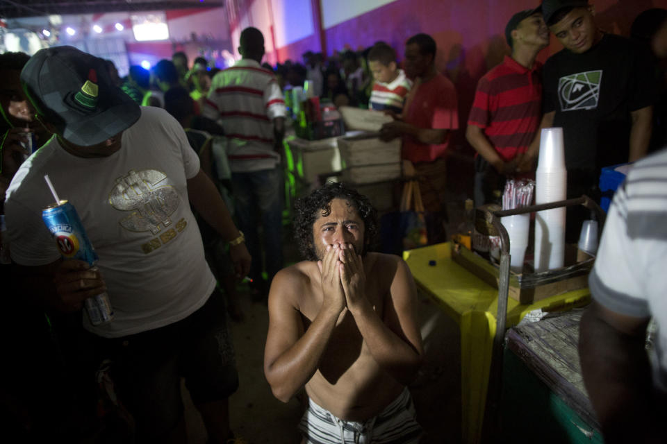 In this Dec. 8, 2012 photo, a man reacts as he kneels on the floor during a funk "baile," or party, in a slum in western Rio de Janeiro, Brazil. A 2007 law that had made it virtually impossible to hold the traditional open-air funk parties in favelas was repealed in 2009, and the musical genre was recognized as a “cultural movement.” (AP Photo/Felipe Dana)