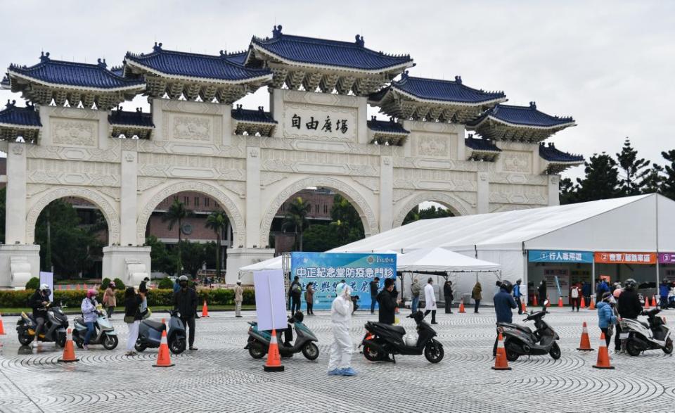 疫情嚴峻，台北市政府和台北榮民總醫院近日在中正紀念堂開設車來速篩檢站，17日正式啟用，現場擺放紅色交通錐，機車騎士、行人上午前往排隊等候採檢。 (中央社)