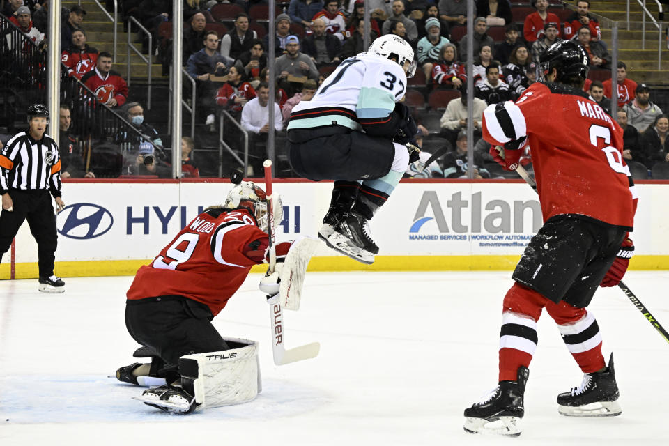 Seattle Kraken center Yanni Gourde (37) jumps as New Jersey Devils goaltender Mackenzie Blackwood (29) has the puck go over his head during the first period of an NHL hockey game Thursday, Feb. 9, 2023, in Newark, N.J. (AP Photo/Bill Kostroun)