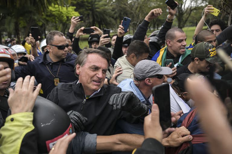 Brazilian President and re-election candidate Jair Bolsonaro greets supporters during a motorcade on the eve of the presidential election, in Sao Paulo, Brazil, on October 1, 2022. - Brazilians go to the polls Sunday in South America's biggest economy, plagued by gaping inequalities and violence, where voters ar expected to choose between far-right incumbent Jair Bolsonaro and leftist front-runner Luiz Inacio Lula da Silva, any of which must garner 50 percent of valid votes, plus one, to win in the first round. (Photo by ERNESTO BENAVIDES / AFP)