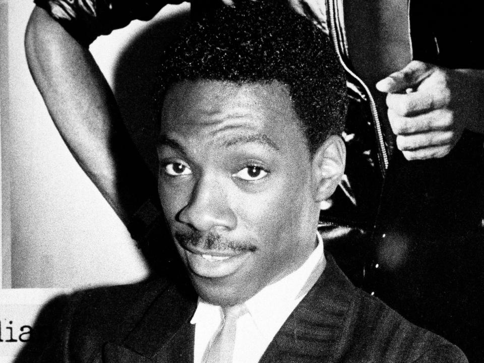 eddie murphy in 1983 poses in front of a poster