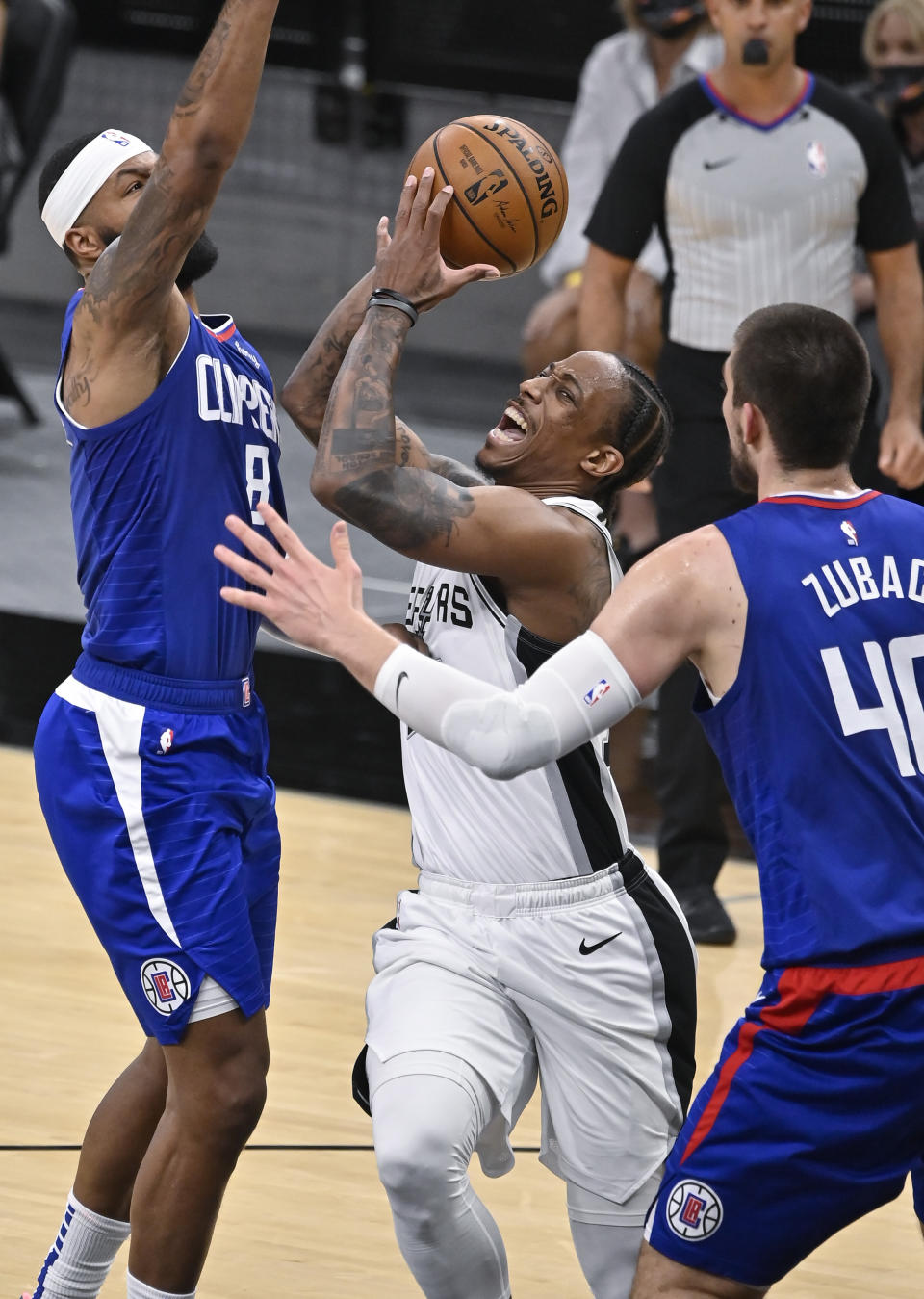 San Antonio Spurs' DeMar DeRozan, center, drives against Los Angeles Clippers' Marcus Morris, Sr. (8) and Ivica Zubac during the first half of an NBA basketball game on Wednesday, March 24, 2021, in San Antonio. (AP Photo/Darren Abate)