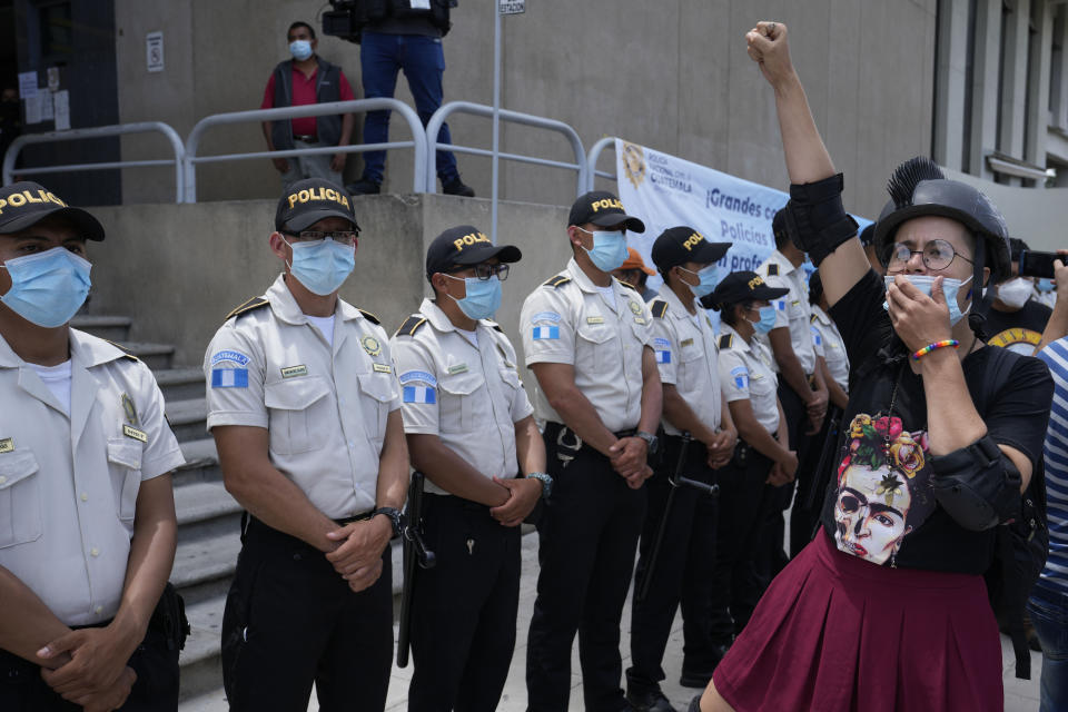 A woman chants before a cordon of police standing guard outside the Attorney General's office as people rallied in support of anti-corruption prosecutor Juan Francisco Sandoval, in Guatemala City, Saturday, July 24, 2021. Sandoval fled Guatemala late Friday, arriving in neighboring El Salvador just hours after he was removed from his post. (AP Photo/Moises Castillo)