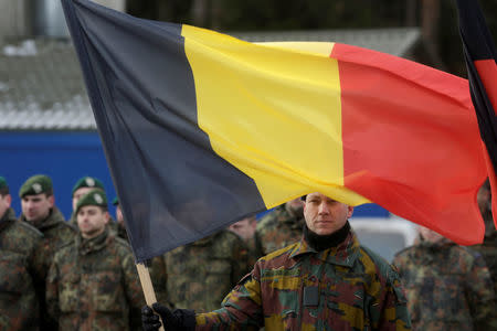 A Belgian soldier holds his national flag during a ceremony to welcome the German battalion being deployed to Lithuania as part of NATO deterrence measures against Russia in Rukla, Lithuania February 7, 2017. REUTERS/Ints Kalnins