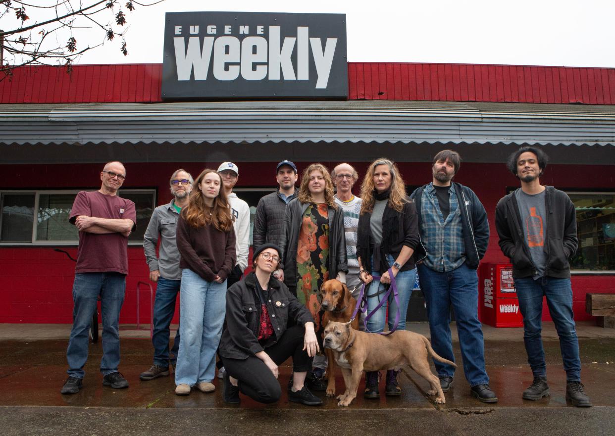 The staff of the Eugene Weekly join editor in chief Camilla Mortensen, center right, and her dogs Biggie and Aksel in front of the paper’s offices in Eugene.