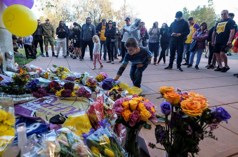 A young fan places a hat at a makeshift memorial for former NBA player Kobe Bryant outside of the Mamba Sports Academy in Thousand Oaks