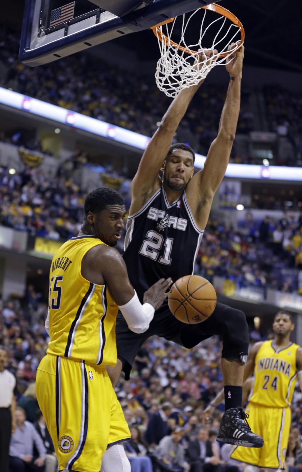 San Antonio Spurs forward Tim Duncan gets a basket on a dunk over Indiana Pacers center Roy Hibbert in the second half of an NBA basketball game in Indianapolis, Monday, March 31, 2014. The Spurs defeated the Pacers 103-77. (AP Photo/Michael Conroy)