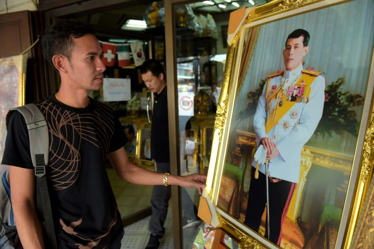 A Thai man looks at a portrait photo of Crown Prince Maha Vajiralongkorn at a shop along a street in Bangkok