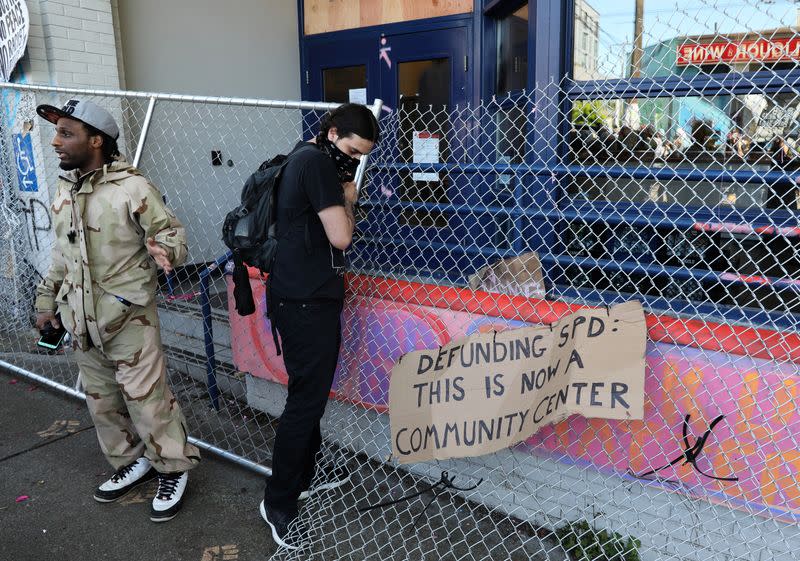 A protester sets up a barricade in front of an entrance of Seattle Police Department East Precinct during a protest against racial inequality and call for defunding of Seattle police, in Seattle