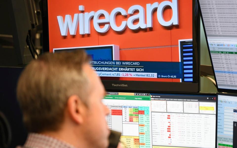 A stockbroker sits in front of a screen with news about the payment service provider Wirecard at the Frankfurt Stock Exchange - Arne Dedert/DPA