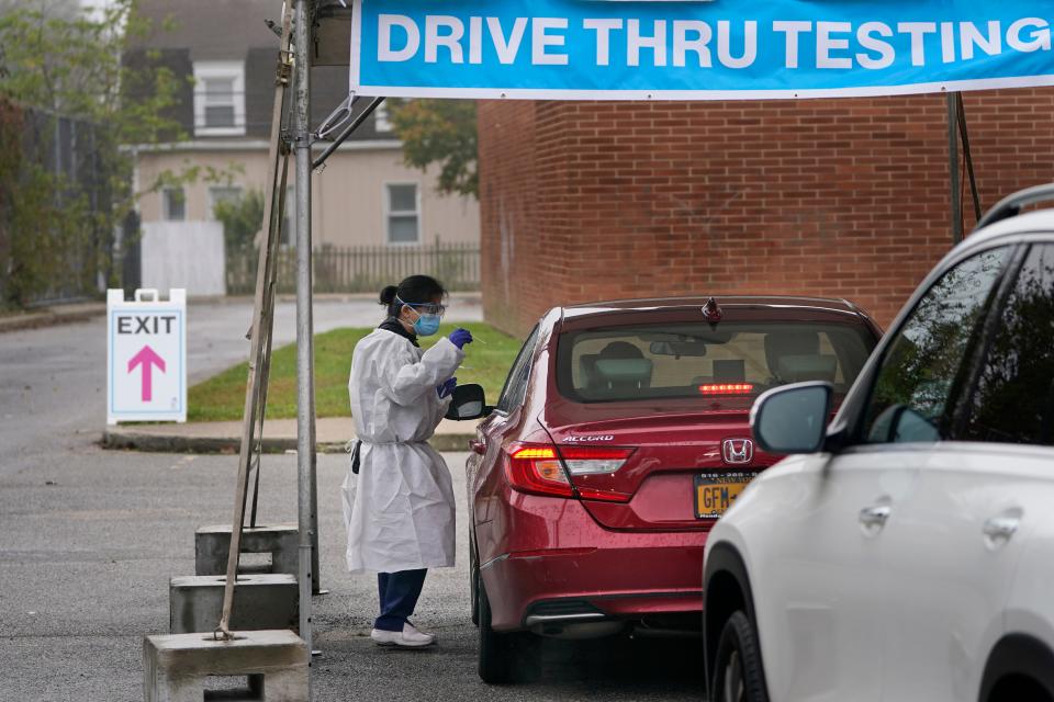 Medical personnel prepare to administer a COVID-19 swab at a drive-through testing site in Lawrence, N.Y., Wednesday, Oct. 21, 2020. The rate of COVID-19 infections has risen enough in New Jersey, Pennsylvania and Connecticut to require those states' residents to quarantine if they travel to New York, but Gov. Andrew Cuomo says New York won't enforce the rules against those residents.