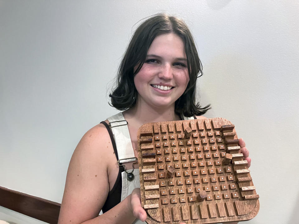 One Stone student Cadence Kirst shows off a handmade wooden game board for the strategy game Quoridor. (Greg Toppo)