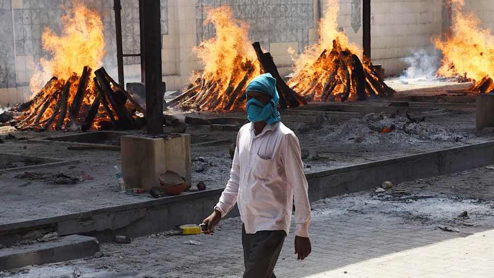 A man is seen here walking past multiple funeral pyres in Covid-ravaged India.