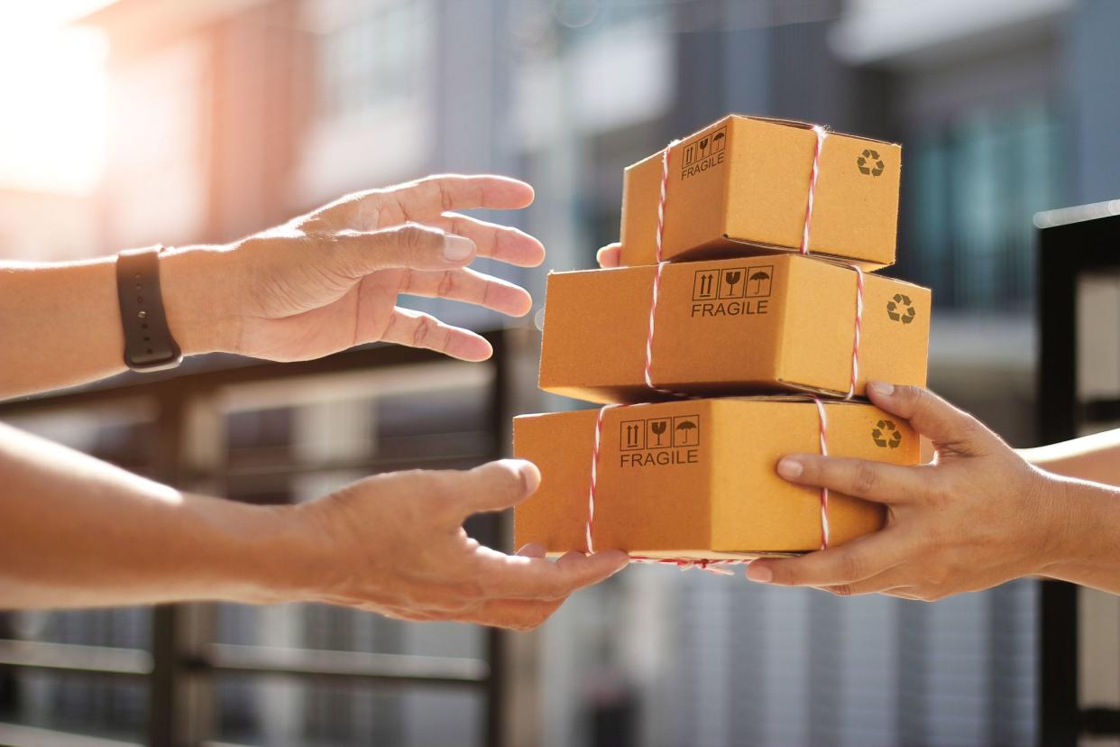 Hands of customer receiving a cardboard boxes parcel from delivery man in the morning, delivery service concept