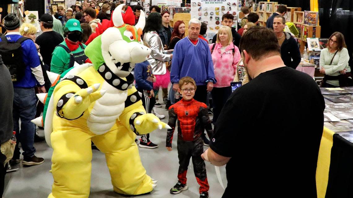 A young patron dressed in Spider-man cosplay gets his picture taken with someone dressed in cosplay as Bowser from Super Mario Bros., on the exhibit floor during the 2022 Lexington Comic and Toy Convention at the Central Bank Center in Lexington, Ky. on Sunday, March 27, 2022. Vendors were selling rare toys and collectibles, comics, art work and pop culture goods from their booths.