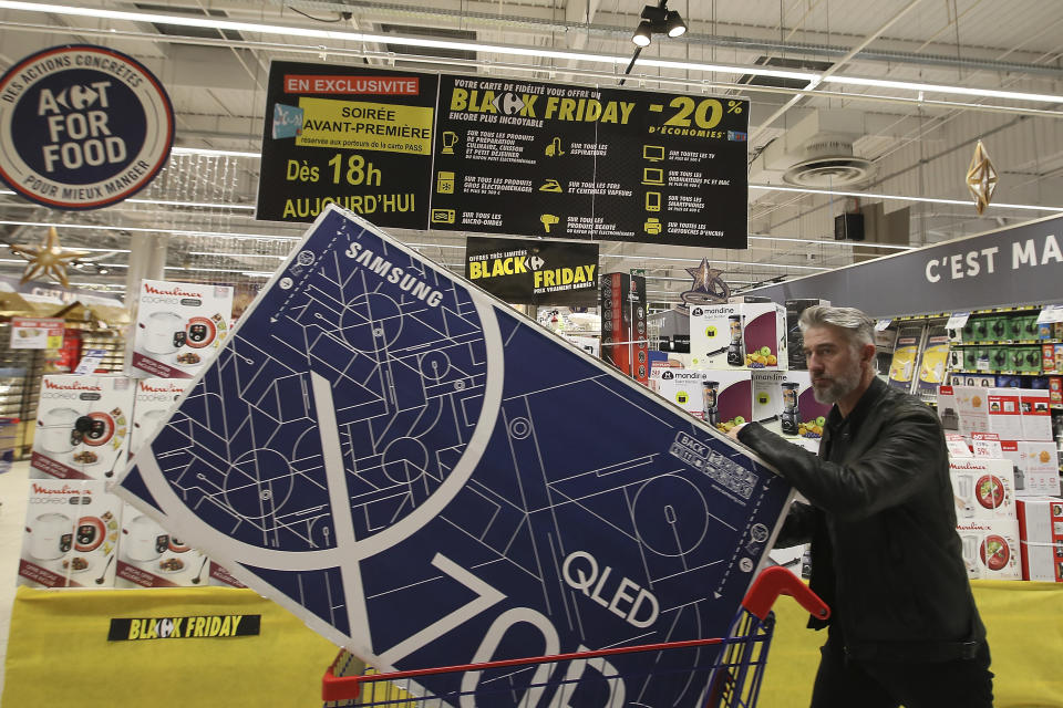 FILE- In this file photo taken on Nov, 28, 2019, a customer walks down the aisle of a shop in the Carrefour Shopping center at the eve of the Black Friday event, in Cesson, western France. In response to the coronavirus, France's government is working to get agreement from the nation's e-commerce sector and supermarket chains to delay the "Black Friday" discount shopping promotion by a week to Dec. 4. (AP Photo/David Vincent, File)