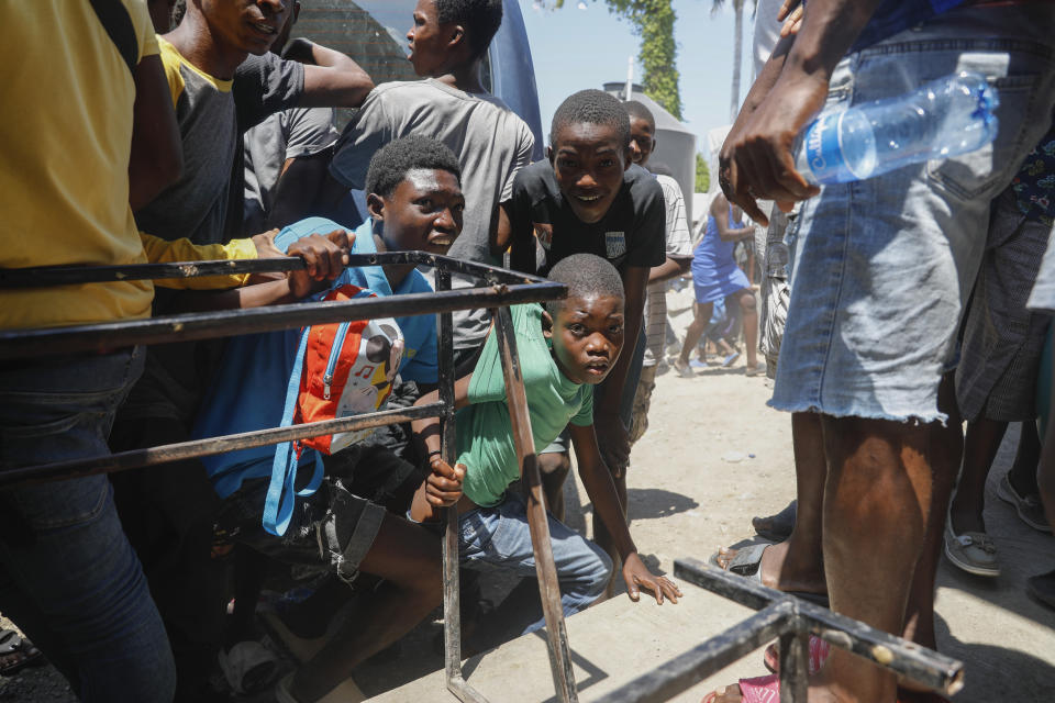 FILE - Youth take cover after hearing gunshots at a public school that serves as a shelter for people displaced by gang violence, in Port-au-Prince, Haiti, March 22, 2024. Children have been forced to flee their homes with their families and are exposed to gang violence. (AP Photo/Odelyn Joseph, File)