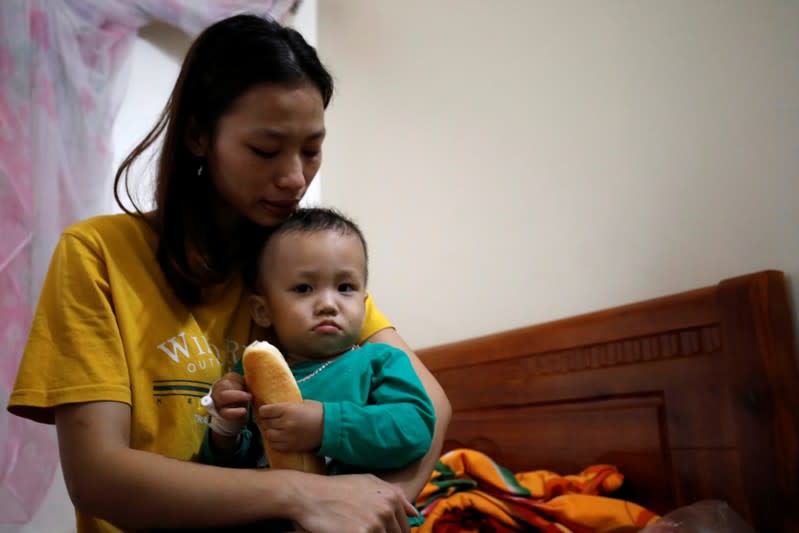 Hoang Thi Thuong, wife of Nguyen Dinh Tu, a Vietnamese suspected victim in a truck container in UK, holds her son Nguyen Dinh Dan at their home in Nghe An province