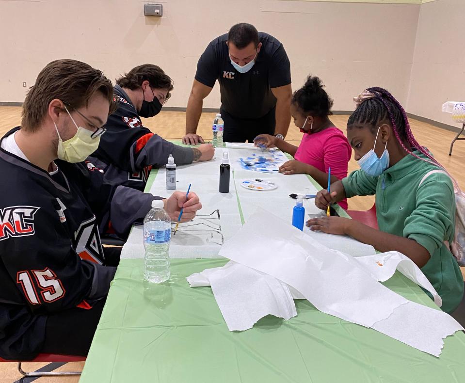 Kansas City Mavericks coach Tad O'Had watches as players and Independence Boys & Girls Club members paint runners for the upcoming Dinner on Ice event Wednesday.