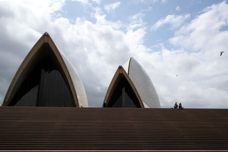 FILE PHOTO: Tourists sit on the mostly deserted steps of the Sydney Opera House