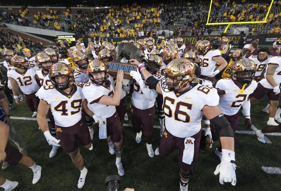 Minnesota quarterback Athan Kaliakmanis (8) and defensive lineman Theorin Randle (99) carry the Floyd of Rosedale trophy after their 12-10 win over Iowa in a NCAA college football game, Saturday, Oct. 21, 2023, in Iowa City, Iowa. (AP Photo/Matthew Putney)
