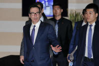 U.S. Treasury Secretary Steven Mnuchin, left, gestures to journalists as he leaves a hotel to attend a new round of high-level trade talks with Chinese officials in Beijing, Thursday, Feb. 14, 2019. (AP Photo/Andy Wong)