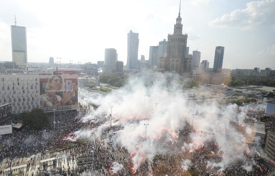 Warsaw residents stand with national flags and flares to observe a minute of silence for the fighters and victims of the 1944 Warsaw Rising against the Nazi German occupiers, on the 74th anniversary of the revolt, in downtown Warsaw, Poland, Wednesday, Aug. 1, 2018. (AP Photo/Czarek Sokolowski)