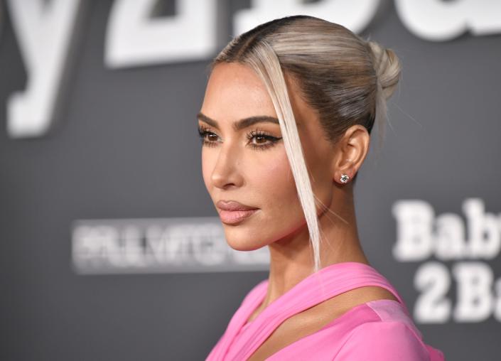 Kim Kardashian wears her platinum blonde hair in a bun while wearing a pink dress at the Baby2Baby event in November 2022.