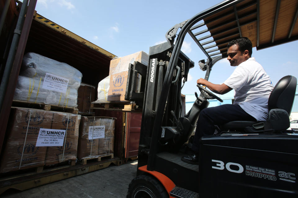 A lift truck driver offloads aid materials for Syria at the UNHCR warehouses in Dubai, part of the International Humanitarian City (IHC), the largest global stockpile for the UNHCR in Dubai, United Arab Emirates, Thursday, Feb. 20, 2014. The UNHCR said it plans to send its aid largest shipment yet to Syria. (AP Photo/Kamran Jebreili)