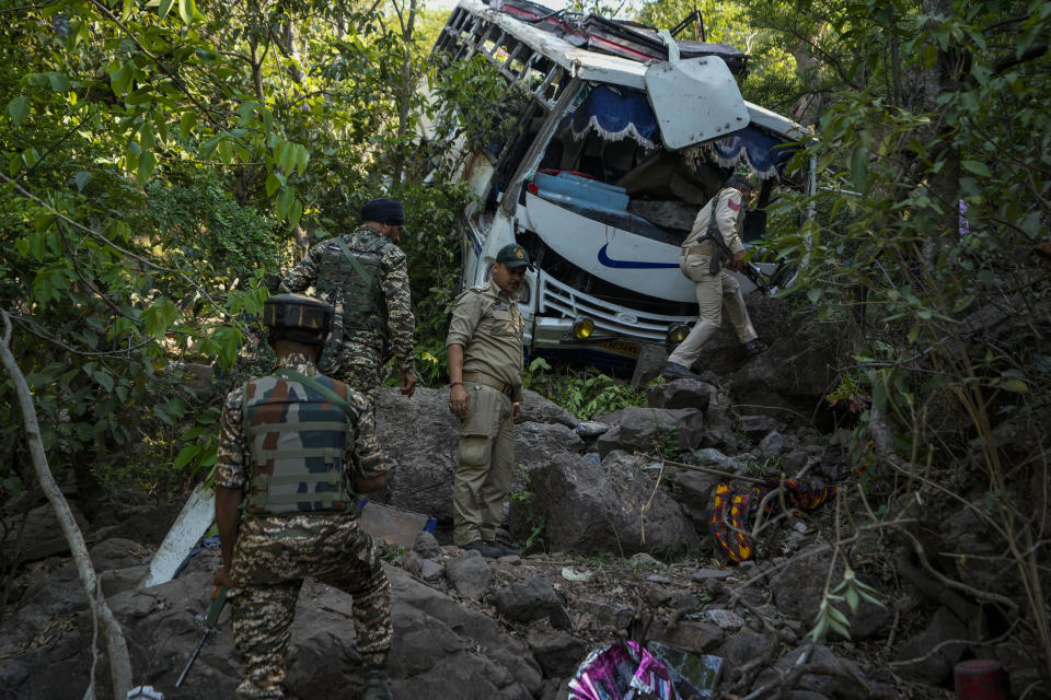 Security men inspect a bus that fell into a deep gorge on Sunday after it was fired at by suspected militants in Reasi district, Jammu and Kashmir, Monday, June 10, 2024. The bus was carrying pilgrims to the base camp of the famed Hindu temple Mata Vaishno Devi when it came under attack killing at least nine people. (AP Photo/Channi Anand)