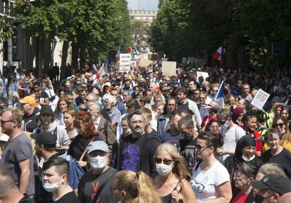 Protesters hold placards during a demonstration against the health pass, in Lille, northern France, Saturday, July 31, 2021. France announced mandatory COVID-19 passes for access to restaurants, bars, shopping malls and many tourist spots, as well as trains and planes, as of July 21. The passes are available to anyone fully vaccinated, recently recovered or who has a recent negative test. (AP Photo/Michel Spingler)