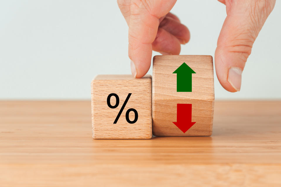 Fingers moving wooden dice with arrows and percentage sign, illustrating a story on CPF investments.