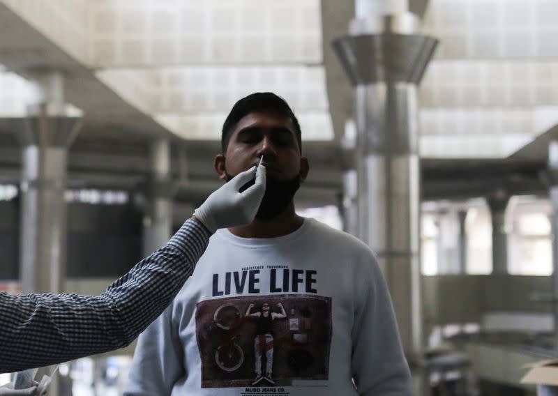 A healthcare worker collects a coronavirus disease (COVID-19) test swab sample from a man at a bus terminal in New Delhi