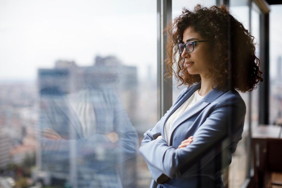 An investor looks pensively out an office window in a city.